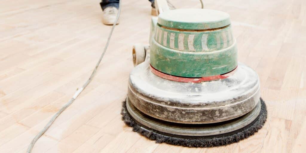 Proces med slibning af gulv med en cirkulær slibemaskine.