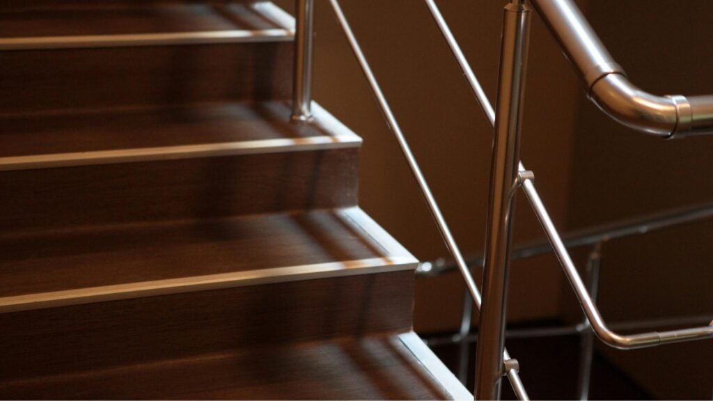 Elegant trappe behandlet med mørk olie, efterfulgt af et lag gennemsigtig lak, akkompagneret af metalliske rækværk.