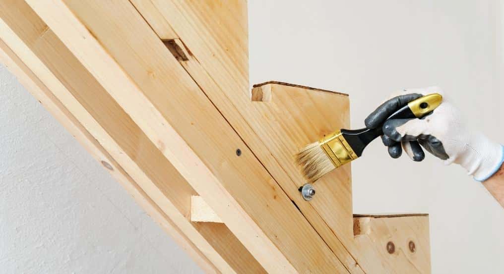 Trætrapper i konstruktionsfasen bliver omhyggeligt lakeret med en pensel for at opnå en glat og beskyttende overflade
