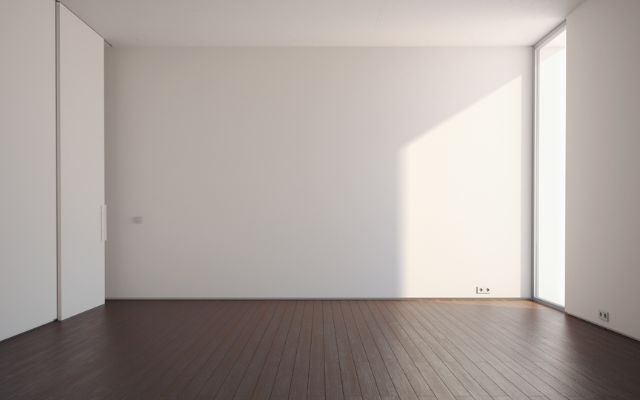 Et tomt rum med hvide vægge og mørkebrunt trægulv er klar til gulvafslibning - et smukt, lyst rum forberedt til gulvforbedring.